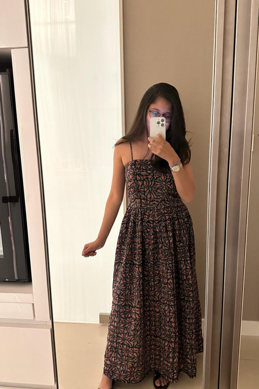 Woman taking a mirror selfie wearing a floral dress in a room.