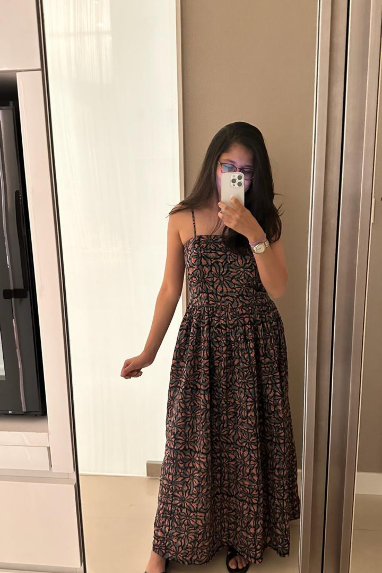 Woman taking a mirror selfie wearing a floral dress in a room.