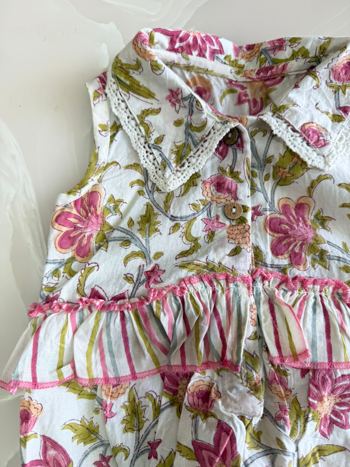 Floral patterned baby outfit with ruffles on a white background
